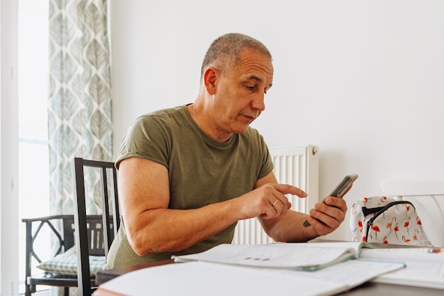 Porträt eines Mannes, der am Laptop arbeitet und zu Hause Notizen im Notizbuch macht