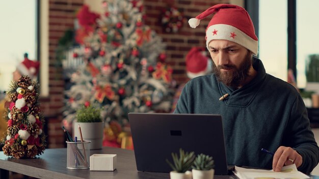 Foto porträt eines mannes, der auf einem tisch sitzt und einen laptop benutzt