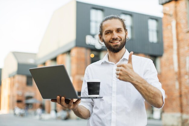 Foto porträt eines mannes, der einen pappbecher mit frischem getränk hat und mit einem partner spricht, der einen video-chat mit einem laptop hat