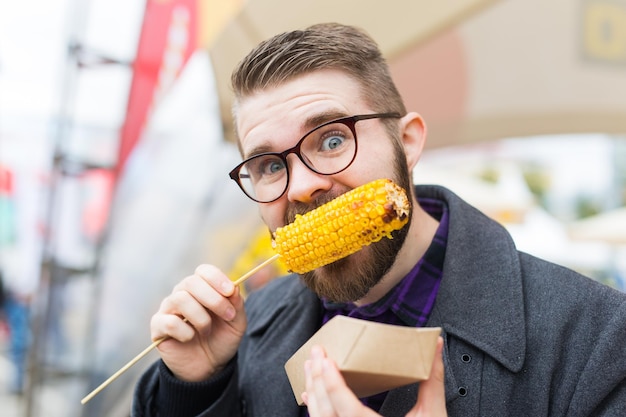 Foto porträt eines mannes, der im freien mais isst