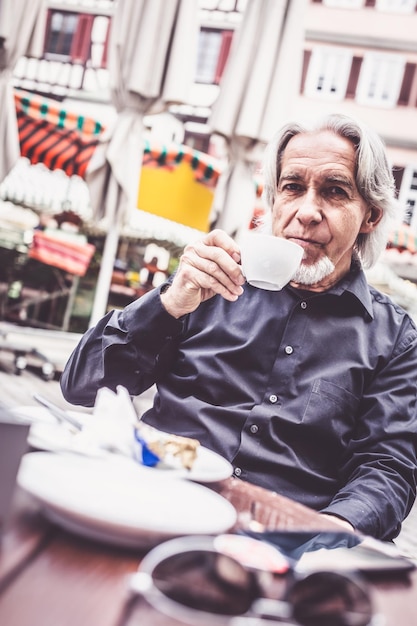 Foto porträt eines mannes, der kaffee im bürgersteigcafé trinkt