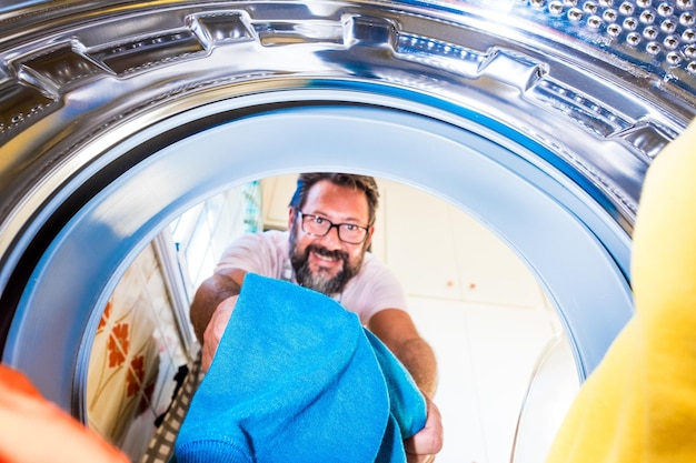 Foto porträt eines mannes, der kleidung in die waschmaschine steckt