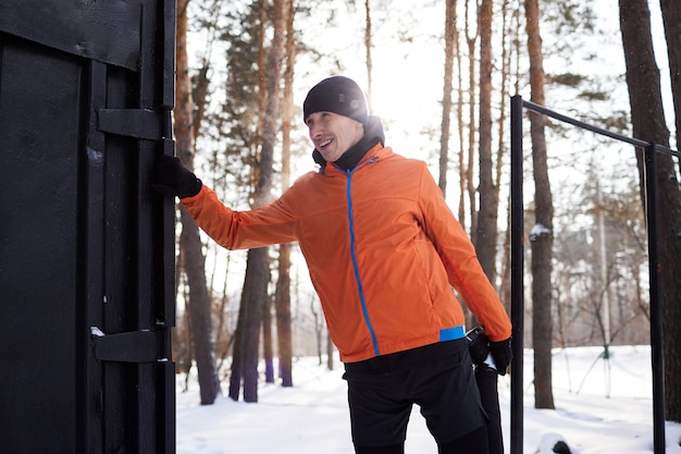 Porträt eines Mannes, der sich im Park an einem schönen verschneiten Wintertag ausdehnt und sich auf das Laufen vorbereitet