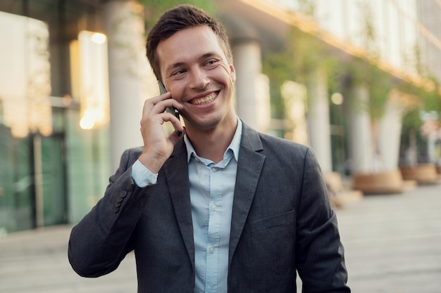 Porträt eines Mannes, ein Banker geht ins Büro und ruft einen Kollegen an und lächelt