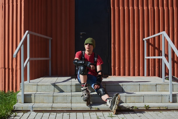 Porträt eines Mannes in Rollschuhen, der auf der Treppe des Gebäudes sitzt