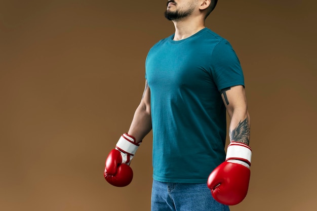 Porträt eines Mannes in roten Boxhandschuhen, der isoliert auf braunem Hintergrund Übungen macht