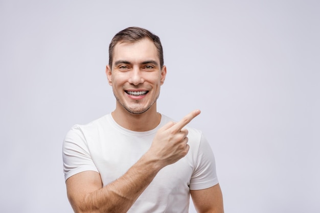 Porträt eines Mannes in weißem T-Shirt zeigt mit dem Finger zur Seite auf weißem Hintergrund für Werbung