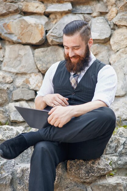 Porträt eines Mannes mit dem Laptop-Computer im Freien