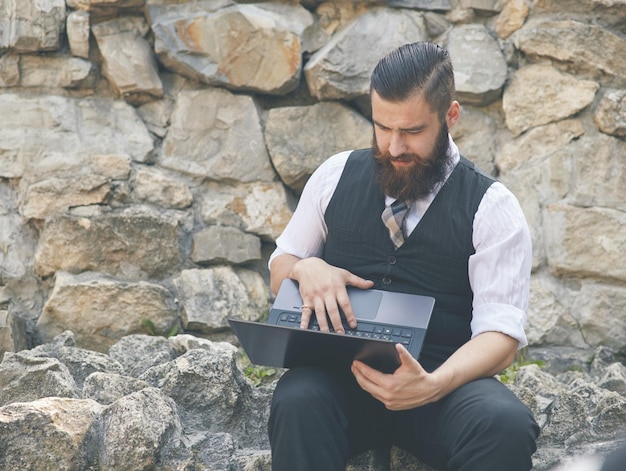 Porträt eines Mannes mit dem Laptop-Computer im Freien