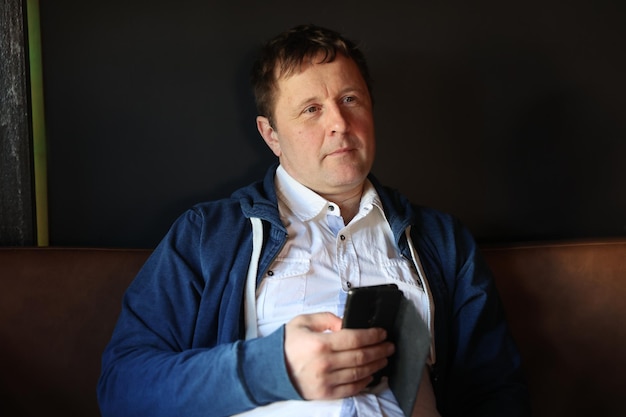 Porträt eines Mannes mit einem Telefon auf einem dunklen Hintergrund