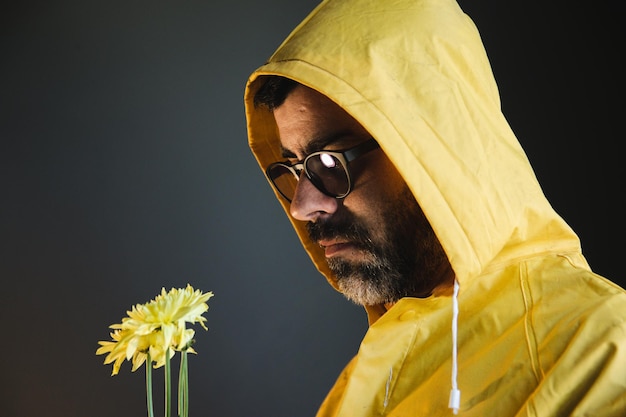 Foto porträt eines mannes mit gelbem regenmantel, der blumen hält