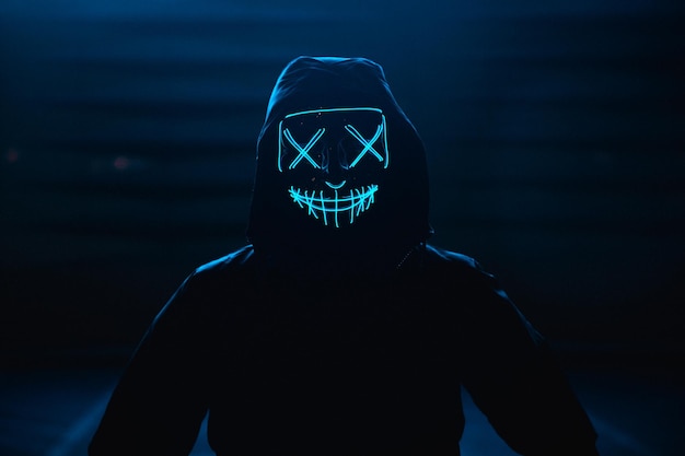 Foto porträt eines mannes mit glühender maske, der vor schwarzem hintergrund steht