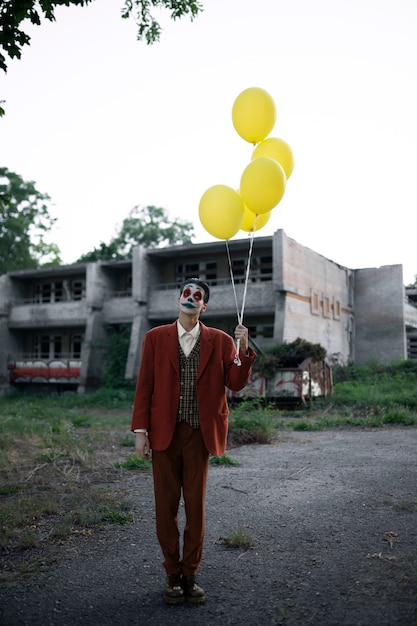 Foto porträt eines mannes mit gruseligem clown-make-up und luftballons