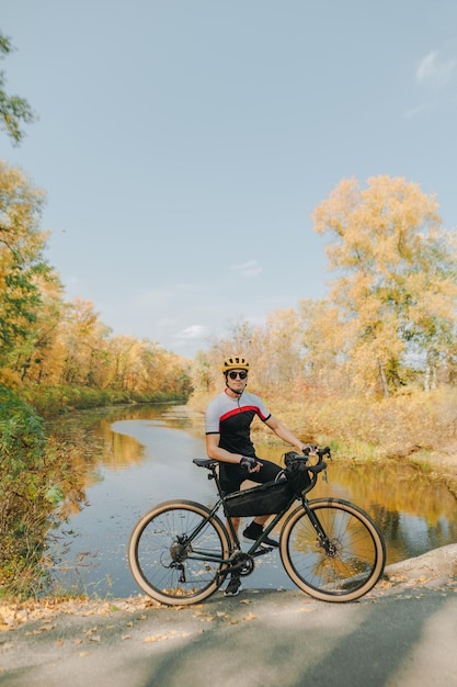 Porträt eines Mannes mit Helm und Sportbekleidung mit Fahrrad bei einem Spaziergang im Park