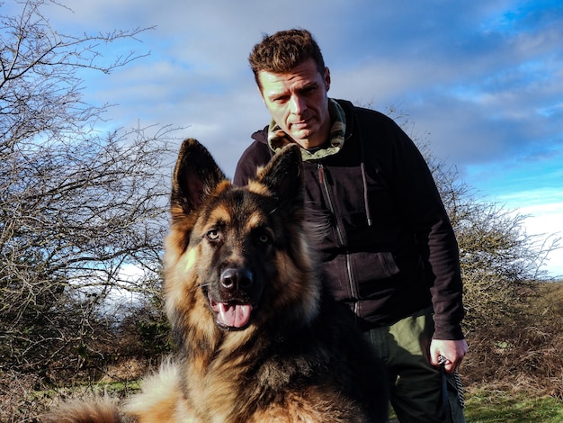 Foto porträt eines mannes mit hund auf dem feld gegen den himmel