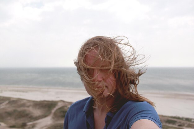 Foto porträt eines mannes mit langen haaren am strand gegen den himmel