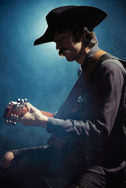 Foto porträt eines mannes mit schnurrbart in kleidung im landhausstil, der gitarre spielt, isoliert über dunkelblau