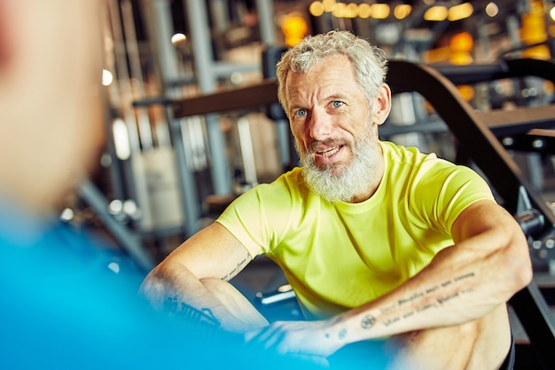 Porträt eines Mannes mittleren Alters, der den Trainingsplan mit einem Fitnesstrainer oder Personal Trainer bespricht