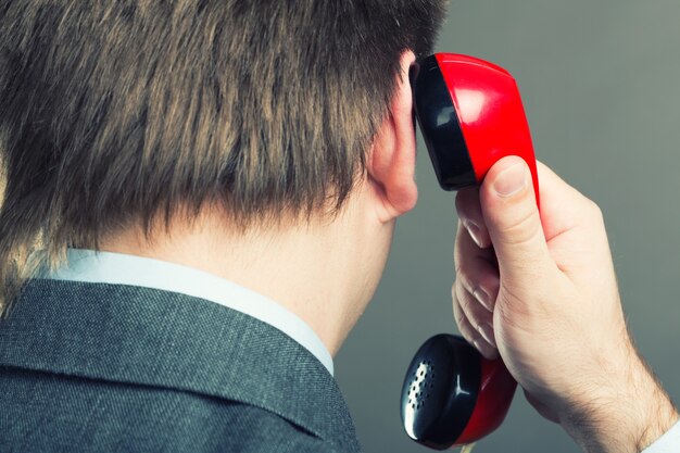 Porträt eines Mannes sprechendes Telefon lokalisiert auf grau