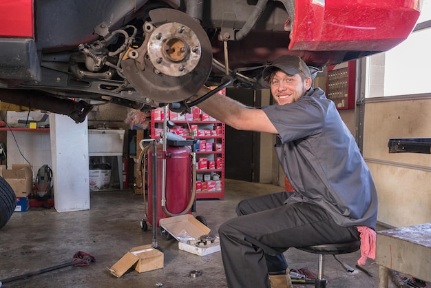 Foto porträt eines mechanikers, der ein auto in der werkstatt repariert