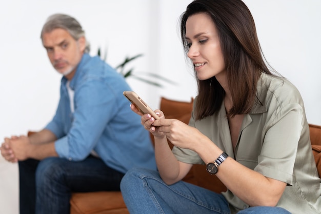 Porträt eines mittleren erwachsenen Paares, das nach Streit auf dem Sofa sitzt.