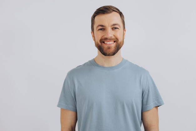 Porträt eines modernen bärtigen Mannes mittleren Alters in einem blauen T-Shirt, das Emotionen auf weißem Hintergrund zeigt