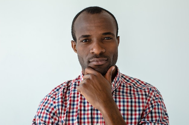 Porträt eines nachdenklichen afroamerikanischen Mannes, der gegen weiße Wand steht, während er eine Wahl trifft