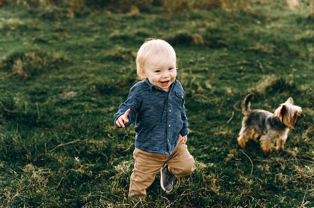 Porträt eines netten Jungen, der durch das Feld bei Sonnenuntergang läuft