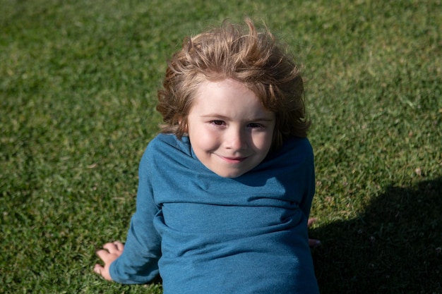 Porträt eines netten Kinderjungen auf Gras im Park. Kaukasisches Kindergesicht hautnah. Nahaufnahmekopf des lustigen Kindes.