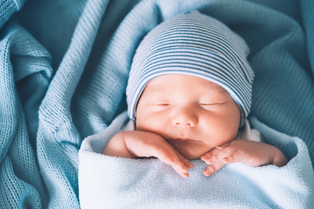 Porträt eines neugeborenen Jungen, der eine Woche alt ist und friedlich in der Krippe im Stoffhintergrund schläft