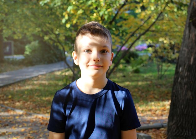 Foto porträt eines neunjährigen blonden jungen in einem herbstpark, ein hübscher kaukasischer junge mit großen augen.