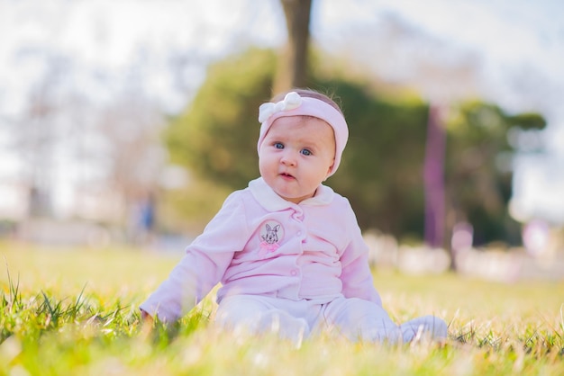 Porträt eines niedlichen Babys, das im Park auf dem Gras sitzt