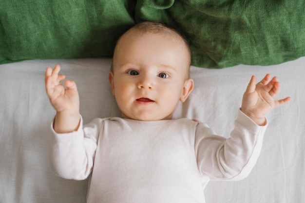 Porträt eines niedlichen, charmanten, lächelnden, lachenden kaukasischen weißen Jungen von sechs Monaten, der auf einem Bett liegt und in die Kamera schaut Blick von oben Ein glücklicher Lebensstil in der Kindheit