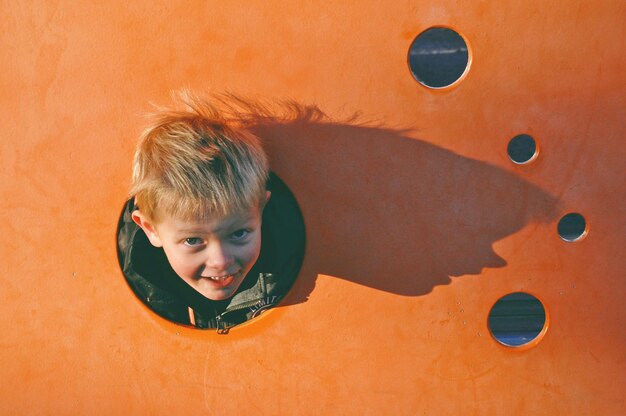 Foto porträt eines niedlichen jungen, der an der wand spielt