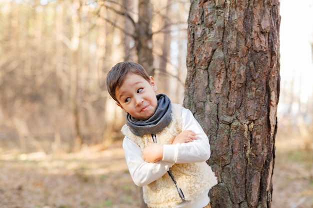 Foto porträt eines niedlichen jungen, der auf einem baumstamm steht