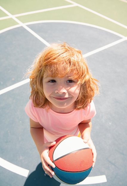 Porträt eines niedlichen Kindes, der Basketball spielt. Kaukasisches lustiges Kindergesicht.