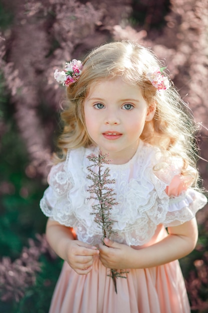 Porträt eines niedlichen kleinen blonden Mädchens mit langen Haaren in einem Vintage-Kleid mit rosa Blumen