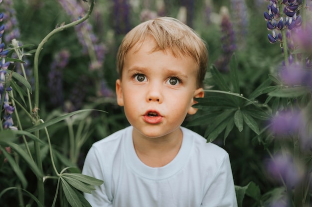 Porträt eines niedlichen kleinen glücklichen Jungen mit Blütenlupinen
