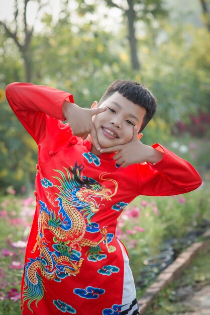 Foto porträt eines niedlichen lächelnden jungen in traditioneller kleidung, der im freien steht