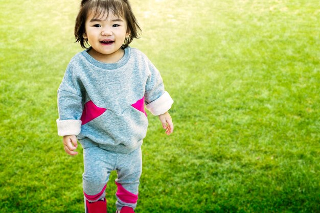 Porträt eines niedlichen Mädchens, das lächelt, während es auf dem Gras steht