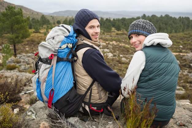 Porträt eines Paares mit dem entspannenden Rucksack während auf einer Wanderung