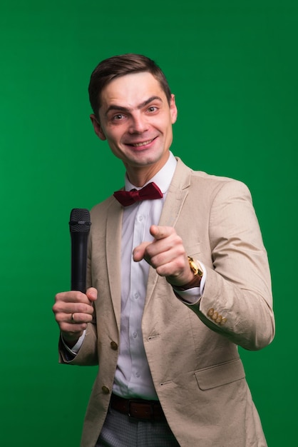 Porträt eines professionellen männlichen Reporters, der ein Mikrofon hält, isoliert auf weißem und grünem Hintergrund