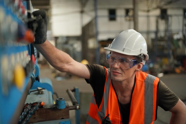 Porträt eines professionellen Schwerindustrieingenieurs / Arbeiters mit Sicherheitsuniform, Schutzbrille und Schutzhelm. Im Hintergrund unfokussierte große Industriefabrik