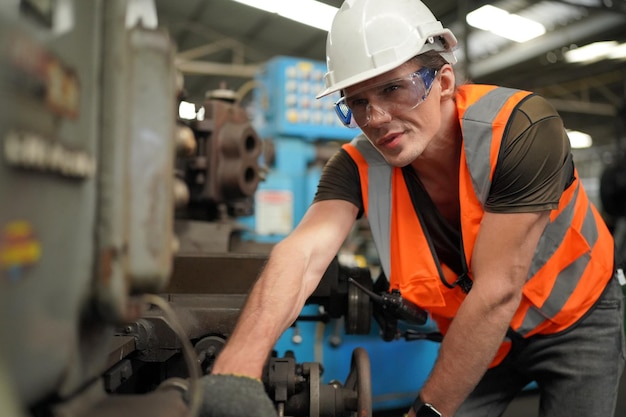 Porträt eines professionellen Schwerindustrieingenieurs / Arbeiters mit Sicherheitsuniform, Schutzbrille und Schutzhelm. Im Hintergrund unfokussierte große Industriefabrik