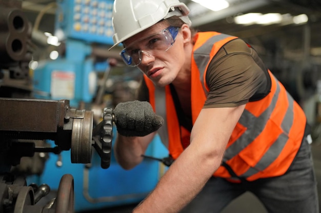 Porträt eines professionellen Schwerindustrieingenieurs / Arbeiters mit Sicherheitsuniform, Schutzbrille und Schutzhelm. Im Hintergrund unkonzentrierte große Industriefabrik