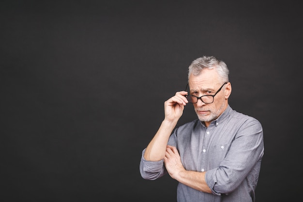 Porträt eines reifen Geschäftsmannes, der eine Brille trägt, die gegen schwarze Wand lokalisiert wird. Glücklicher älterer Mann mit Kopierraum. Schließen Sie herauf Gesicht des glücklichen erfolgreichen Geschäftsmannes.