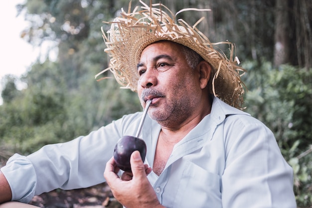 Porträt eines reifen Mannes, ländlicher Stil, der den typischen Aufguss in Argentinien und Uruguay namens Mate trinkt.