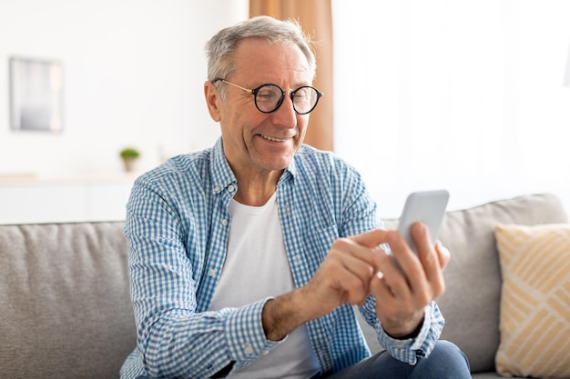 Porträt eines reifen Mannes mit Smartphone auf der Couch sitzend