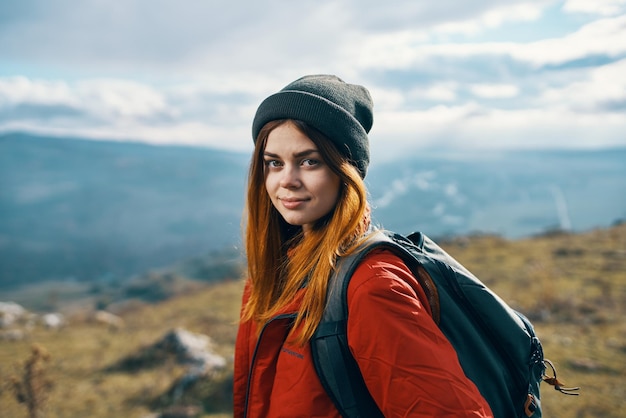 Porträt eines Reisenden in roter Jacke, Hut und Rucksack draußen in den Bergen an der frischen Luft