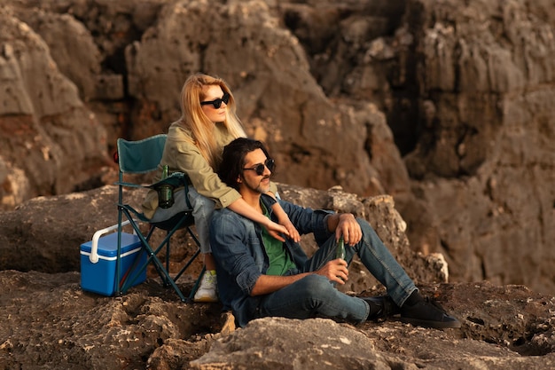 Porträt eines romantischen jungen Paares, das draußen auf Felsen ein Picknick macht und sich umarmt